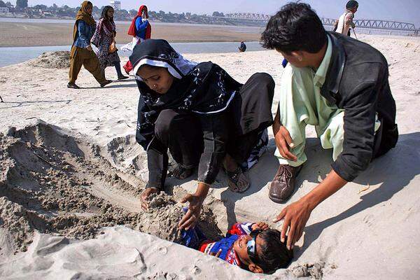 In Pakistan wurden behinderte Kinder halb im Sand begraben, weil den abgedunkelten Sonnenstrahlen heilsame Wirkung zugeschrieben wird.