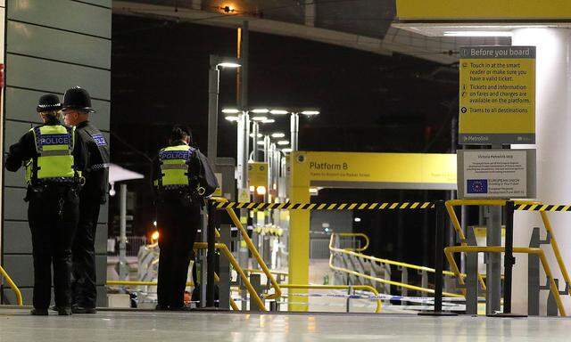 Police officers stand at the end of a tram platform following a stabbing at Victoria Station in Manchester