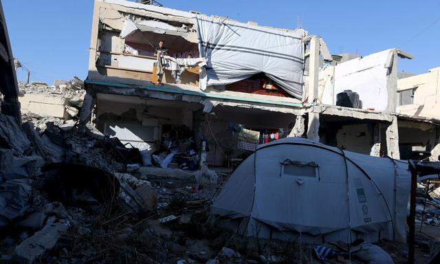 A Palestinian man fixes a cover over the wreckage of of his house in Khan Younis