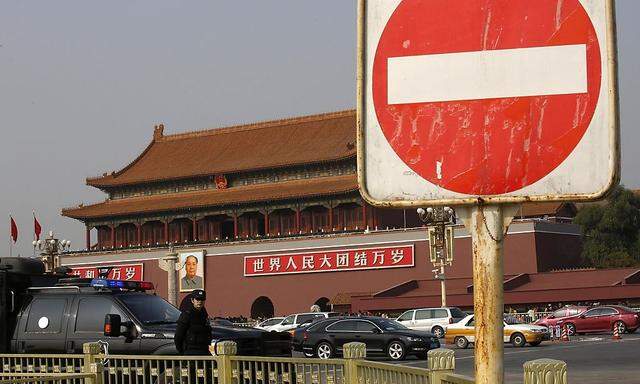 A sign is seen next to a policeman of the SWAT team standing guard in front of the giant portrait of Chinese late Chairman Mao on Tiananmen Square in Beijing