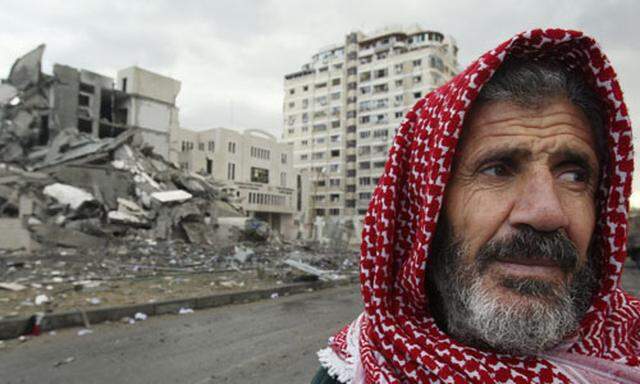 A Palestinian man walks past a Hamas government building destroyed after an Israeli air strike in Gaza