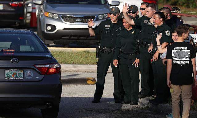 Die US-Polizei winkt ankommenden Schülern der Marjory Stoneman Douglas High School, die zwei Wochen nach dem Massaker, wieder in den Unterricht zurückkehren.