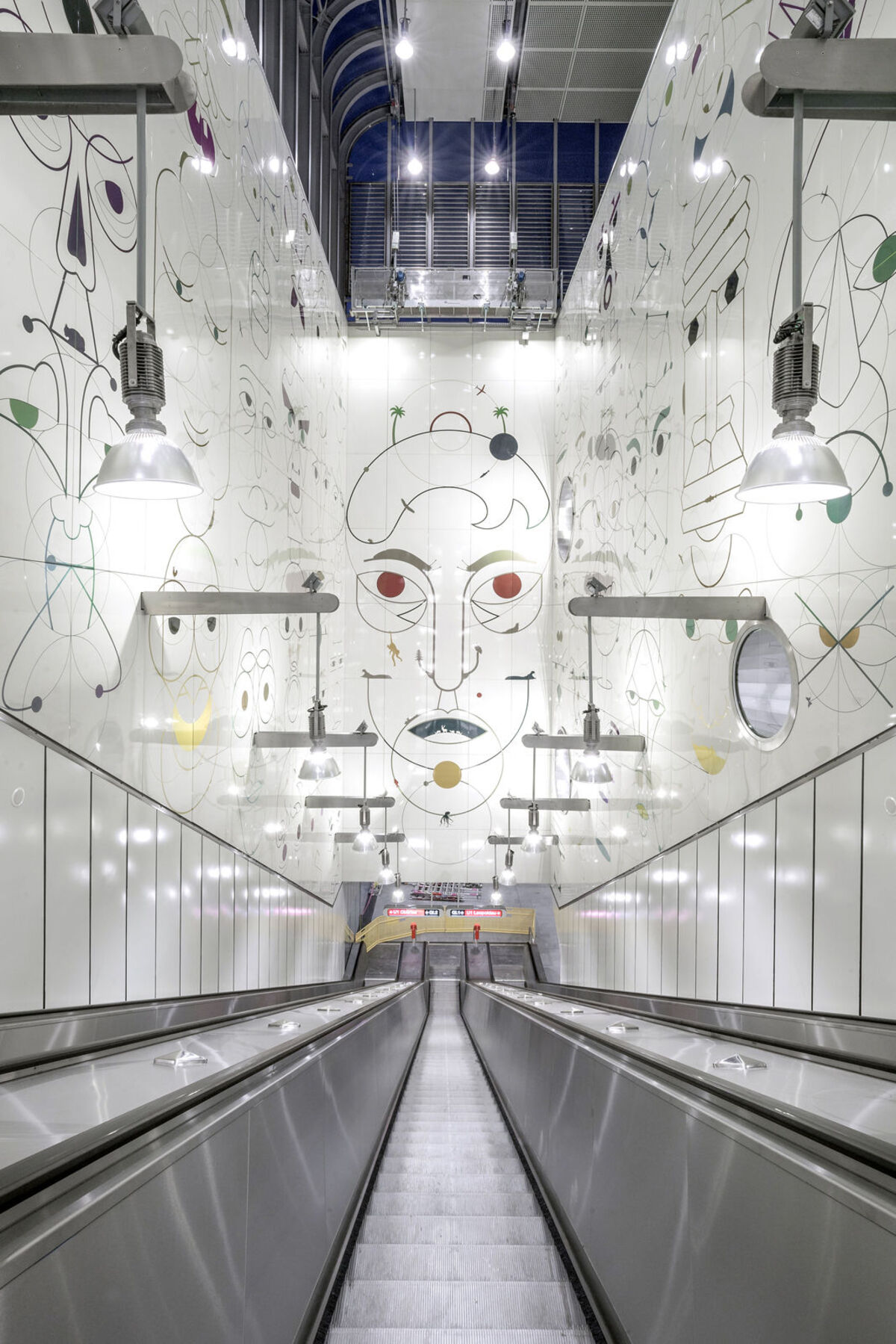 Station Altes Landgut. Das Kunstwerk "Gesichtsüberwachungsschnecken" von Yves Netzhammer über der 50 Meter langen Rolltreppe.