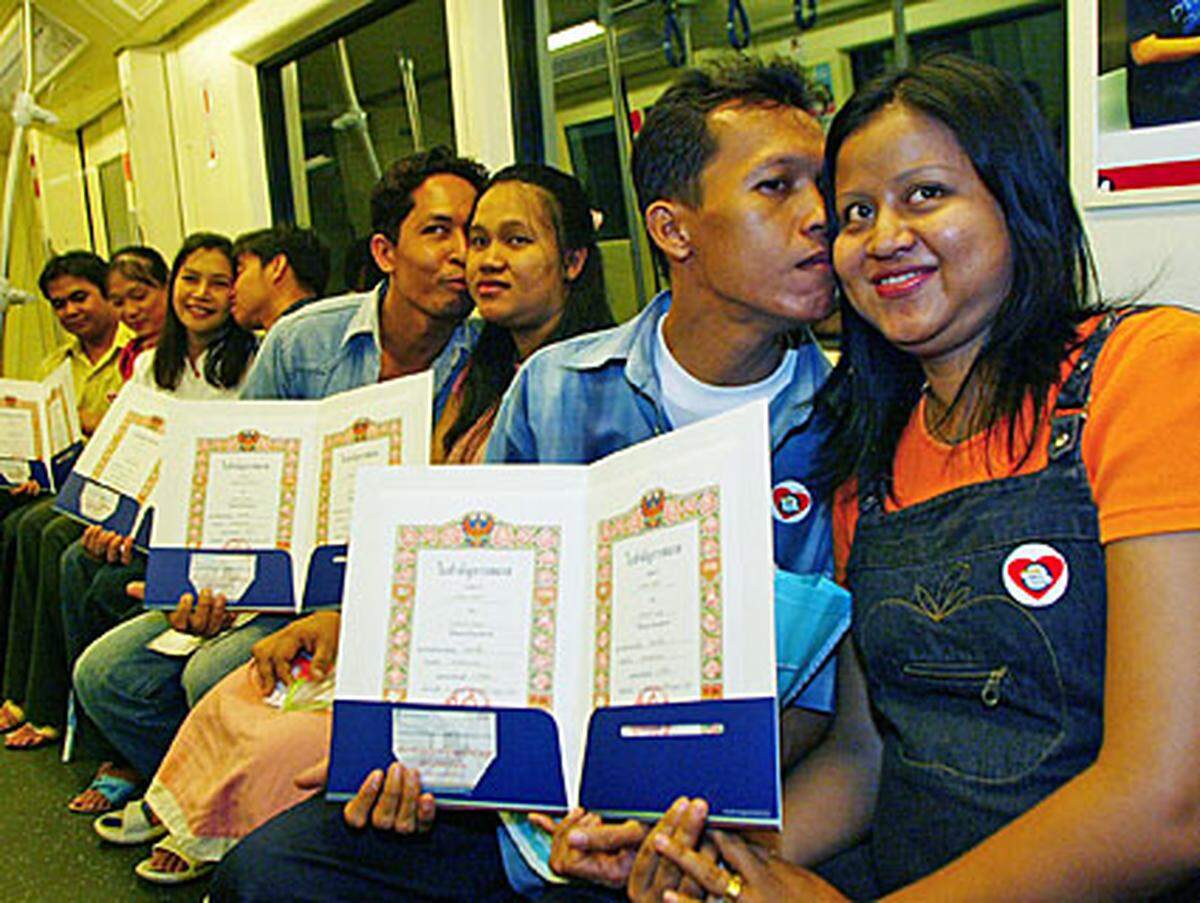 Da fährt der Zug drüber. Frisch Vermählte präsentieren in der thailändischen U-Bahn ihre Heiratsurkunden. Am Valentinstag entschlossen sich 200 Paare in einer U-Bahnstation mit dem Namen "Dorf der Treue" zu heiraten.