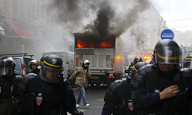 Riot police officers move back from a burning truck during clashes with youths in Lyon, central Franc