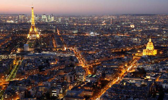 A general view shows the illuminated Eiffel Tower, the Hotel des Invalides and rooftops at night in Paris