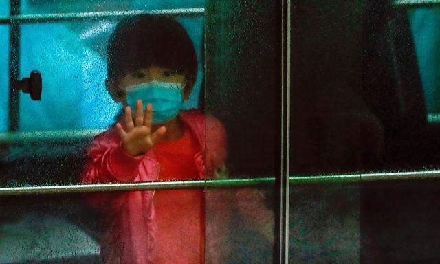 Ein Kind winkt aus einem Fahrzeug in Hongkong, als es aus einem Gebäude in Sicherheit gebracht wird, in dem das neue Coronavirus Covid-19 ausgebrochen ist.