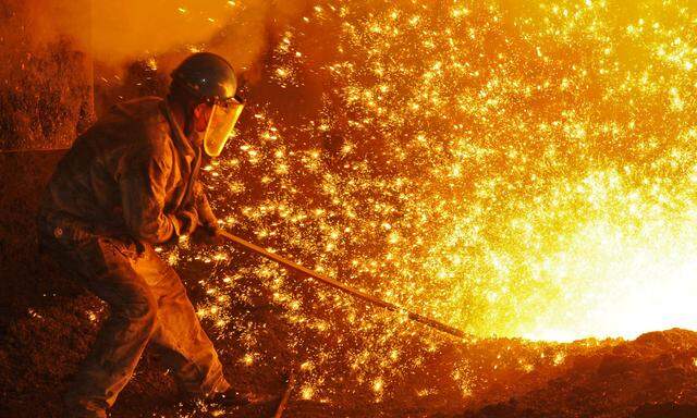 An employee works next to molten iron at a steel mill of Dongbei Special Steel in Dalian