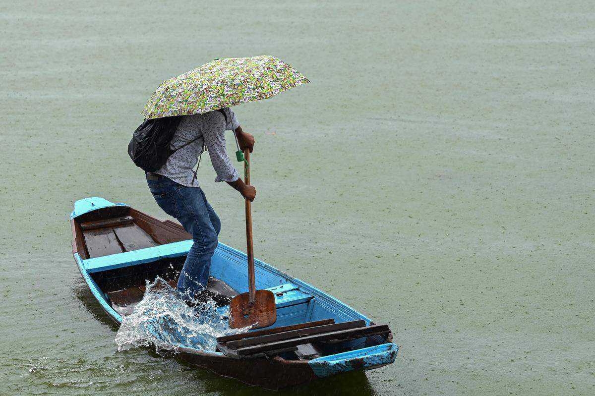 22. Juli. Ein Inder schaufelt mit einem Ruder Wasser aus seinem Boot am Dal Lake in Srinagar. Aktuell herrscht Monsunzeit in Südasien. Der starke Regen verursacht oft große Schäden, immer wieder sterben auch Menschen. Gleichzeitig ist er für die Landwirtschaft lebenswichtig. 