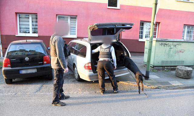 Polizisten mit einem Spürhund durchsuchen ein Auto.