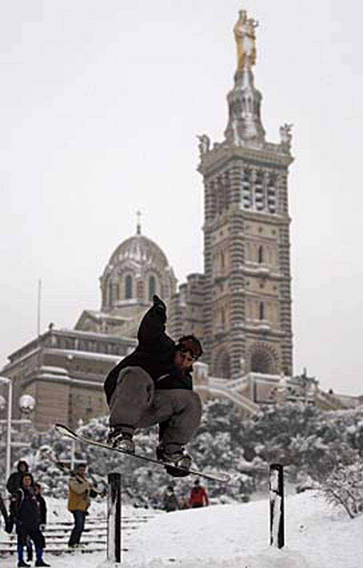In der französischen Mittelmeer-Hafenstadt liegen mehrere Zentimeter Schnee. Snowboarder nutzen die sanfte Erhöhung, auf der die Basilika Notre Dame de La Garde steht.
