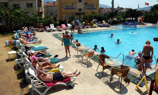 Tourists, most of them British tourists of the travel firm Holidays 4U, rest by the pool side at a holiday resort in Mugla