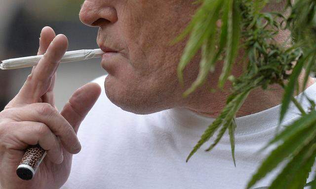 FILE PHOTO: A man prepares to smoke a cannabis cigarette at a legalise cannabis tea party outside the Houses of Parliament, in London
