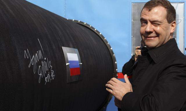 Russian President Medvedev gestures after writing 'Good Luck!' on a pipe of the Nord Stream pipeline near Russian town of Vyborg