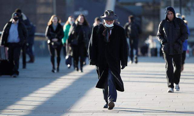 Commuters walk across London Bridge amid the spread of the COVID-19, in London