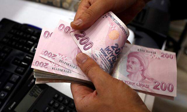 A money changer counts Turkish lira banknotes at a currency exchange office in Istanbul