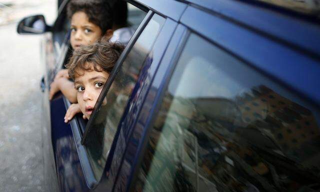 Palestinian children look out a car window driving past the rubble of a residential tower, which witnesses said was destroyed in an Israeli air strike in Gaza City