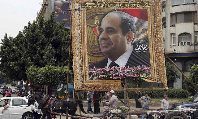 An Egyptian man on horse cart rides past a huge banner for Egypt's former army chief Field Marshal Abdel Fattah al-Sisi in downtown Cairo