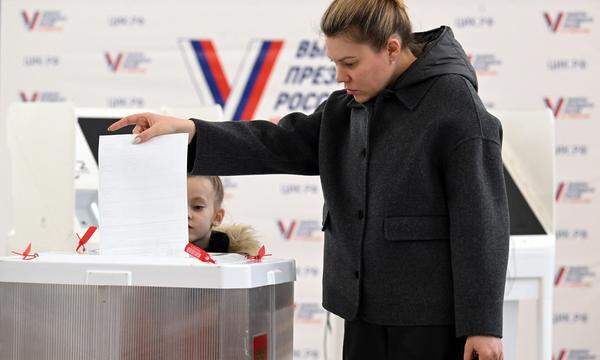 A woman with her child votes in Russia's presidential election in Moscow on March 16, 2024. (Photo by NATALIA KOLESNIKOVA / AFP) (Photo by NATALIA KOLESNIKOVA/AFP via Getty Images)