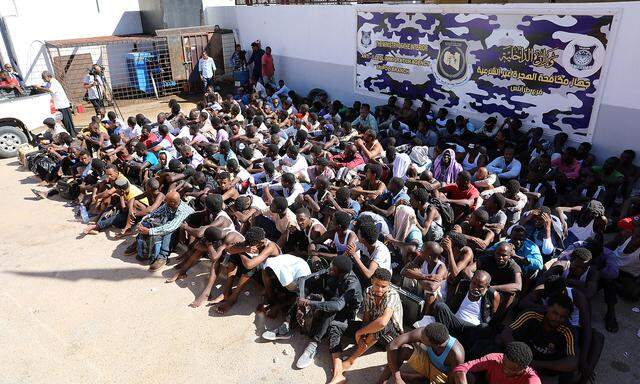 Sudanese migrants sit at a detention center before their voluntary return to their country, in Tripoli