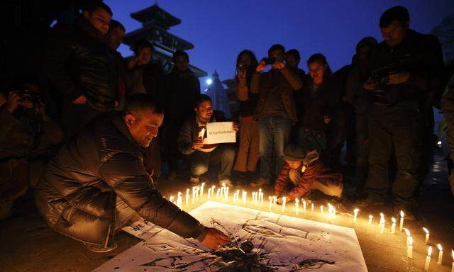 A journalist draws a cartoon during a candle light vigil organised by the Federation of Nepalese journalist to pay tribute to victims of Wednesday´s shooting by gunmen at the offices of French weekly newspaper Charlie Hebdo in Paris, in Kathmandu