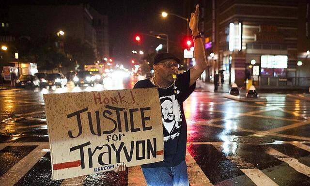 Will Reese holds a protest sign in response to the acquittal of George Zimmerman in the Trayvon Martin trial, in the Harlem neighborhood of New York