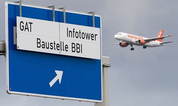 A planes approaching Schoenefeld SFX airport flies near a sign denoting the motorway exit to the building site of the Berlin Brandenburg international airport in Schoenefeld