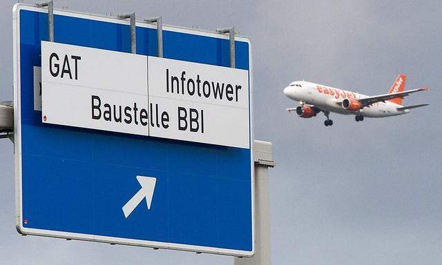 A planes approaching Schoenefeld SFX airport flies near a sign denoting the motorway exit to the building site of the Berlin Brandenburg international airport in Schoenefeld