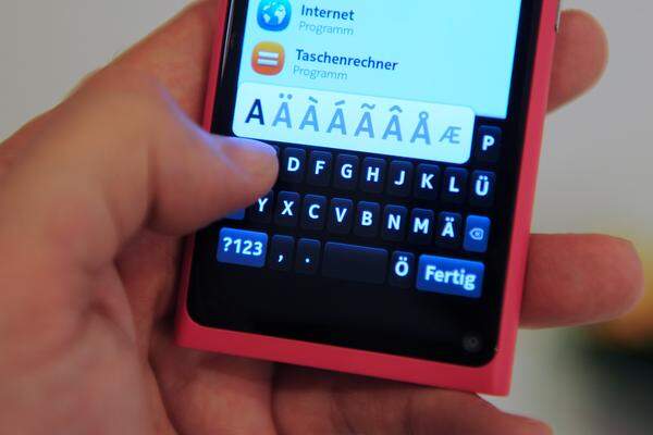Was wäre ein Smartphone ohne Bildschirmtastatur? Die beim N9 integrierte wirkt etwas klein, lässt sich aber reibungslos und flott benutzen. Oben im Bild sieht man die Suchfunktion für Apps, die von Haus aus beim Gerät inkludiert ist.