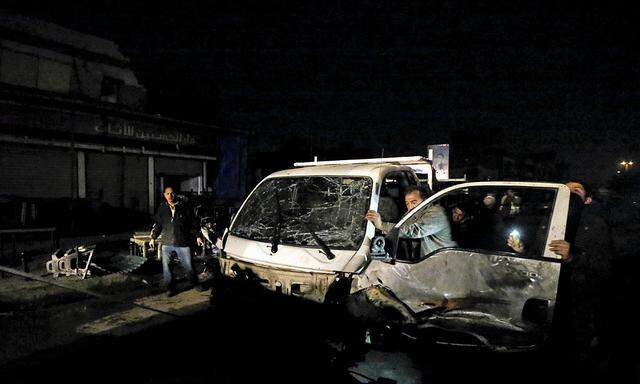 A man pushes his damaged car away from the site of a car bomb attack in New Baghdad