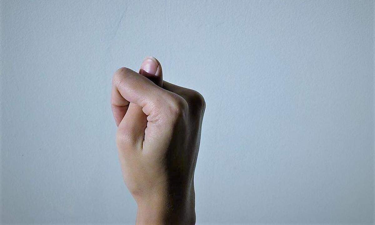 Daumen zwischen Zeigefinger und Mittelfinger: Bedeutung der Feigenhand