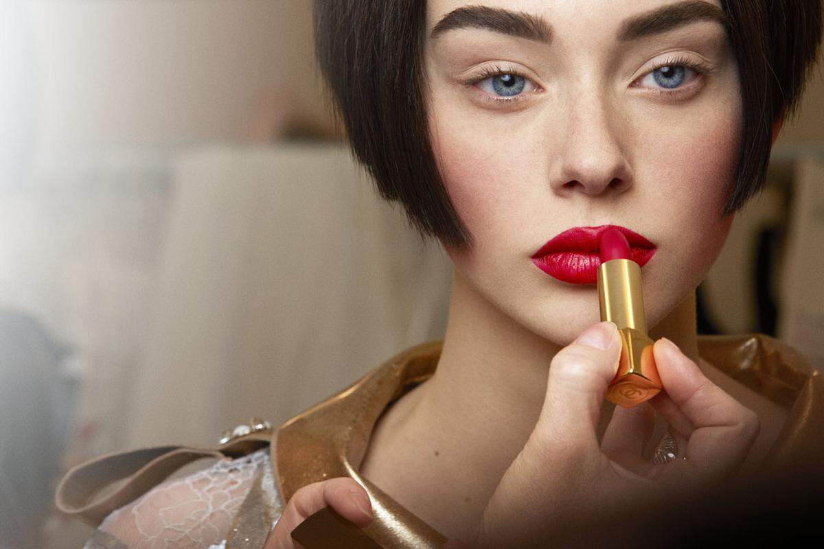 Die intensiv gezeichneten Augenbrauen runden die strenge Frisur ab, auf den Lippen kam der neue Lippenstift Rouge Allure Velvet N°51 in "La Bouleversante", der ab Oktober erhältlich sein wird, zur Geltung.