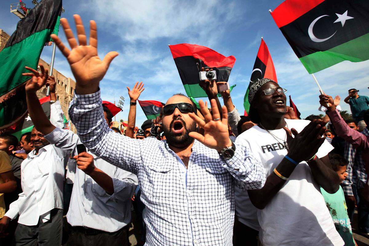 Die Menschen schwenken die neue libysche Flagge ...