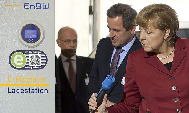 EnBW AG CEO Mastiaux explains the operation of an electric car charging booth to German Chancellor Merkel at the Electric Mobility Conference of German government in Berlin