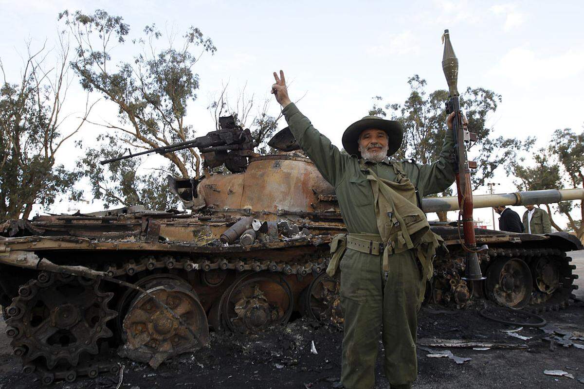 Ein Kämpfer der Rebellen vor einem ausgebrannten Panzer.