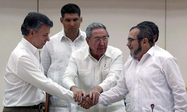 Raul Castro hält die Hände von Kolumbiens Präsident Santos und FARC-Führer Timochenko.