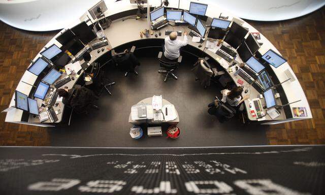 Traders work at their desks below the DAX board at the Frankfurt stock exchange