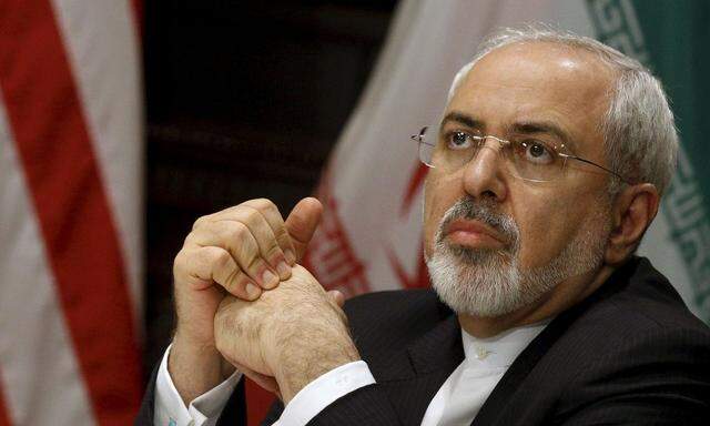 Zarif listens as Kerry speaks to the media during a meeting in New York