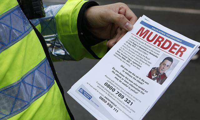 A police officer poses for a photograph with a leaflet appealing for witnesses to the murder of British soldier Lee Rigby in Woolwich, southeast London
