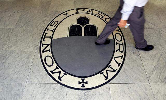 A man walks on a logo of the Monte Dei Paschi Di Siena bank in Rome