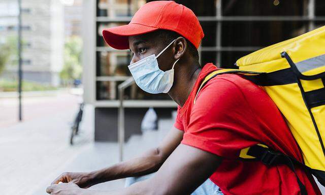 Young delivery man wearing protective face mask during COVID-19 model released Symbolfoto XLGF02315