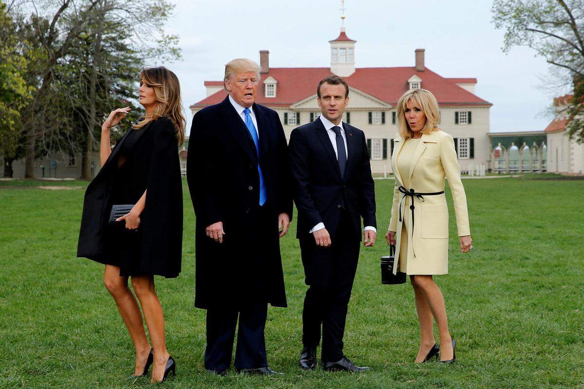 Macron trägt erneut Louis Vuitton, Melania Trump ein schwarzes Kleid von Dolce &amp; Gabbana samt Cape von Givenchy. In Sachen Modemut geht der Punkt an Melania, dafür ist ein Cape nicht von allen Blickwinkeln vorteilhaft.