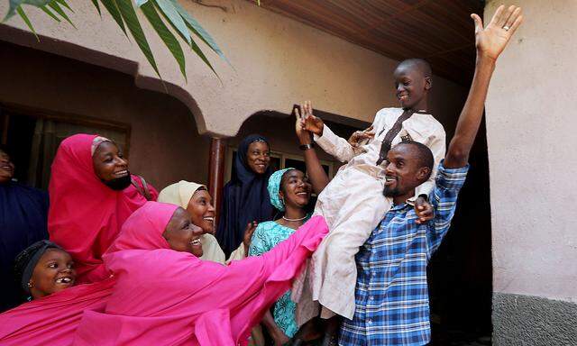 Muhammed Bello, a rescued student, is carried by his father as his relatives celebrate after he retuned home in Kankara