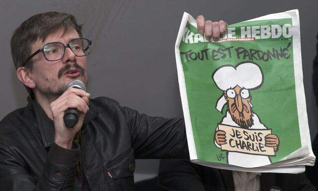 Satirical French magazine Charlie Hebdo cartoonist Luz holds a copy of their next issue during a news conference in Paris