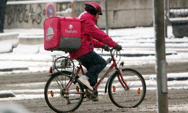 Fahrradkurier vom Internet Portal Foodora liefert warme Speisen aus in der verschneiten Innenstadt F