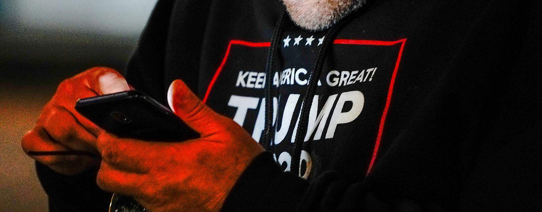 FILE PHOTO: A man wearing a 'Trump 2020' sweatshirt uses his mobile phone during a 'Stop the Steal' protest outside Milwaukee Central Count the day after Milwaukee County finished counting absentee ballots, in Milwaukee