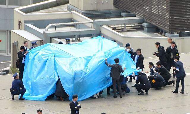 Police and security officers investigate an unidentfied drone which found on the rooftop of Prime Minister Shinzo Abe's official residence in Tokyo