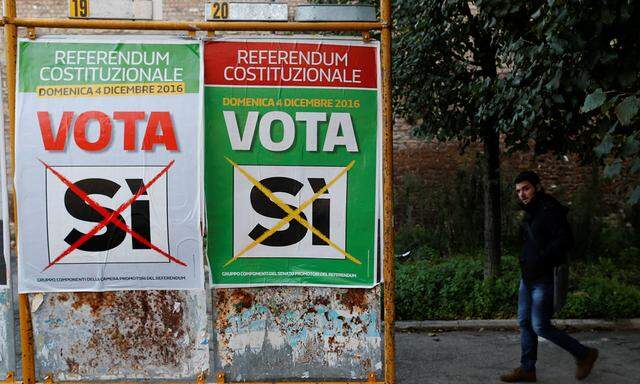 A man walks next to a poster in support of the ´Yes´ vote in the upcoming constitutional reform referendum in Rome