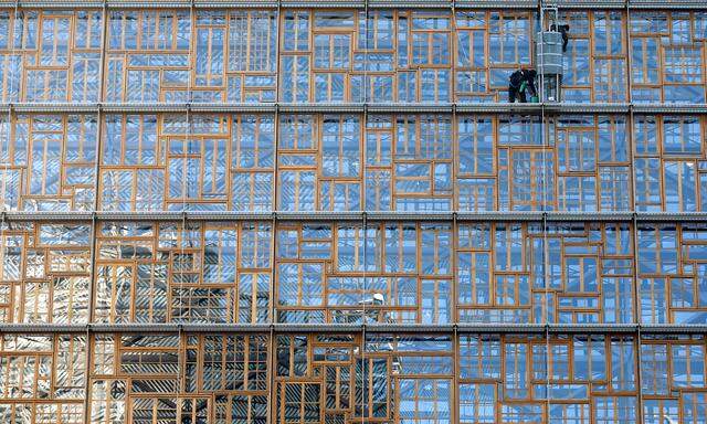 Window cleaners work on the facade of the EU Council building in Brussels