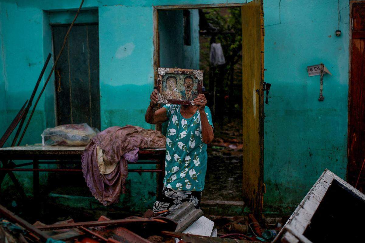 Eine Frau hält ein Bild ihrer Eltern hoch, das sie in ihrem vor 40 Jahren durch ein Hochwasser zerstörten Zuhause in Brasilien fand.